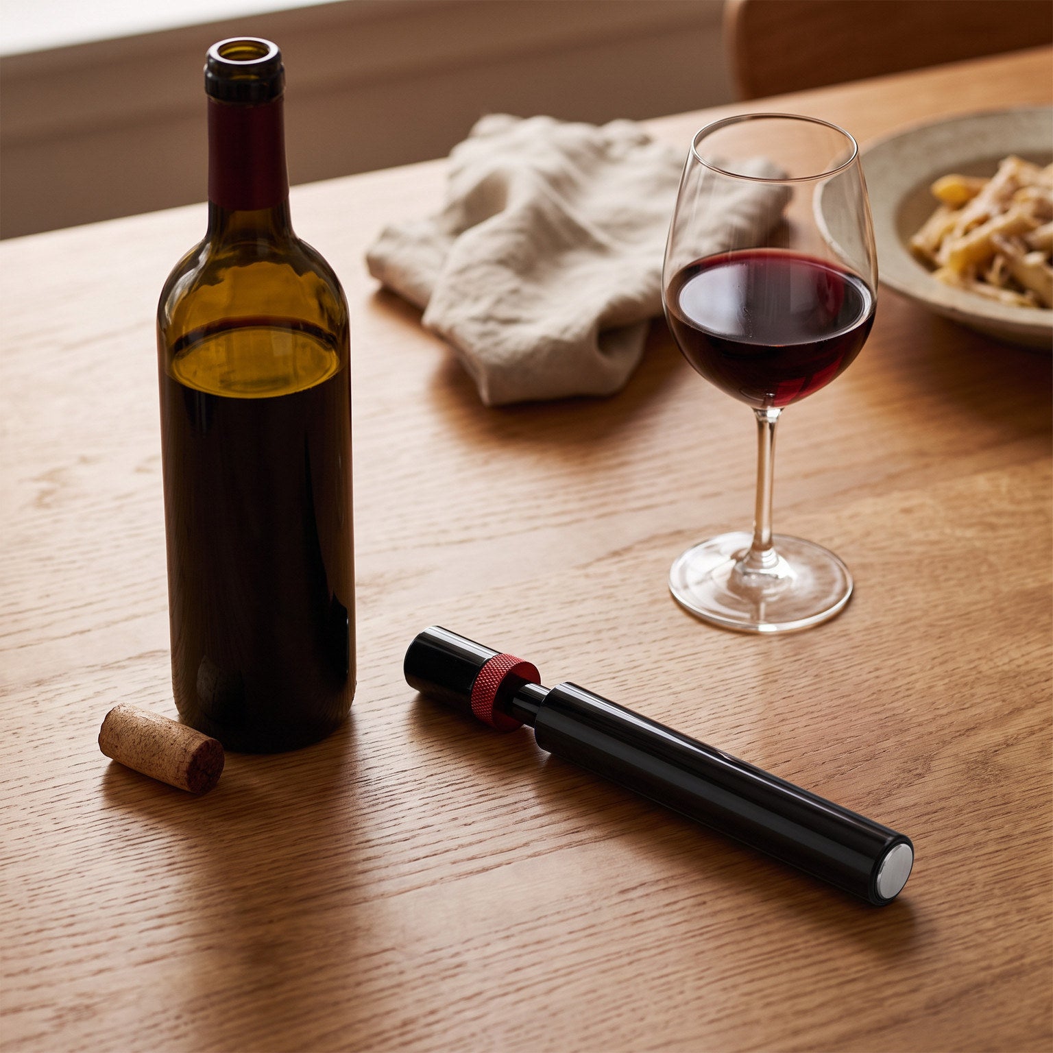Red Openvale opener beside a natural-cork wine bottle at a dinner table